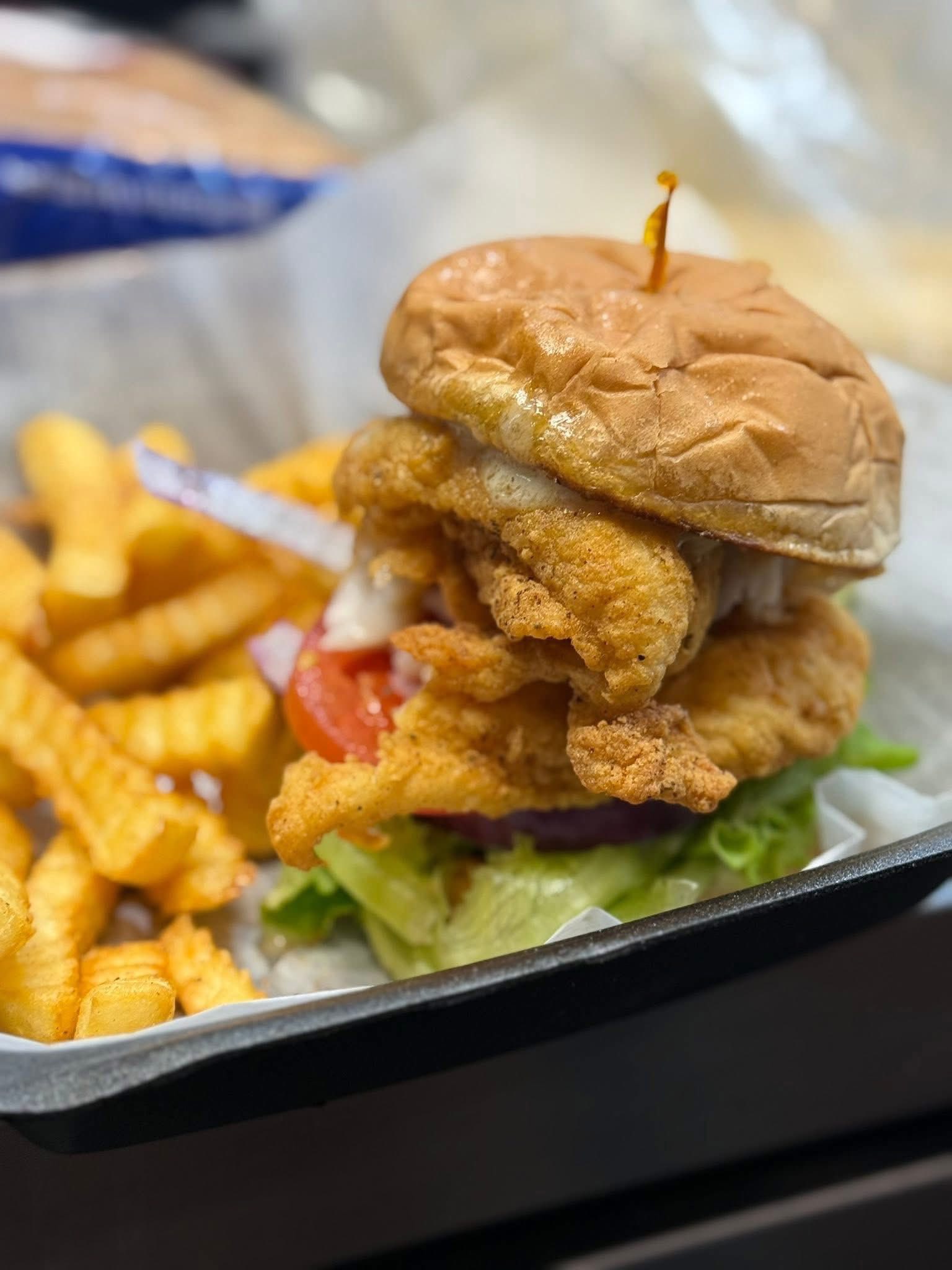 Golden fried chicken sandwich on croissant bun with fries